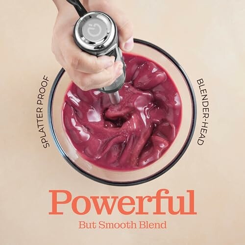 Hand blending a red smoothie in a bowl.