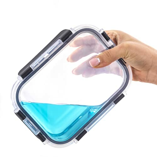 Hand holding a transparent leak-proof container with blue liquid inside.