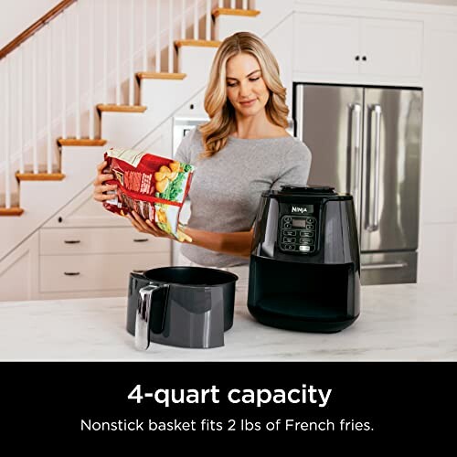 Woman using a Ninja air fryer in a kitchen.